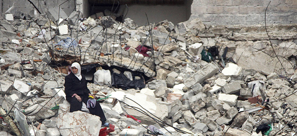 In this Wednesday, Feb. 6, 2013 photo, a Syrian woman sits on the ruins of her house, which was destroyed in an airstrike by government warplanes a few days earlier, killing 11 members of her family, in the neighborhood of Ansari, Aleppo, Syria. (AP Photo/Abdullah al-Yassin)
