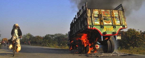 A bus set on fire by Islamist activists burns on a street as a Bangladeshi man rides his bicycle during a clash with Jamaat-e-Islami activists in Rajshahi north-west from Dhaka on February 28, 2013. At least 30 people were killed in Bangladesh in a wave of violence today as Islamists reacted furiously to a ruling that one of their leaders must hang for war crimes during the 1971 independence conflict. At least 22 of them were shot in clashes between police and protesters that erupted after Delwar Hossain Sayedee, the Jamaat-e-Islami party's vice president, was found guilty of war crimes, including murder, arson and rape. AFP PHOTO/Stringer (Photo credit should read -/AFP/Getty Images)