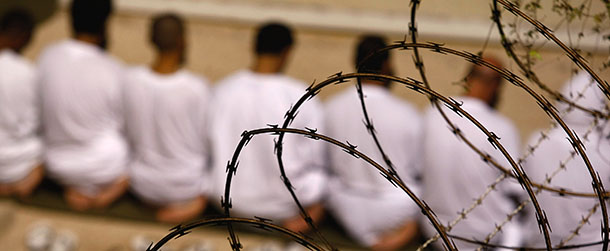 GUANTANAMO BAY, CUBA - OCTOBER 28: (EDITORS NOTE: Image has been reviewed by U.S. Military prior to transmission) A group of detainees kneels during an early morning Islamic prayer in their camp at the U.S. military prison for "enemy combatants" on October 28, 2009 in Guantanamo Bay, Cuba. Although U.S. President Barack Obama pledged in his first executive order last January to close the infamous prison within a year's time, the government has been struggling to try the accused terrorists and to transfer them out ahead of the deadline. Military officials at the prison point to improved living standards and state of the art medical treatment available to detainees, but the facility's international reputation remains tied to the "enhanced interrogation techniques" such as waterboarding employed under the Bush administration. (Photo by John Moore/Getty Images)