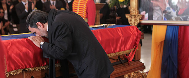 In this photo released by Miraflores Press Office, Iran's President Mahmoud Ahmadinejad kisses the flag-draped coffin of late Venezuela's President Hugo Chavez during the funeral ceremony at the military academy in Caracas, Venezuela, Friday, March 8, 2013. Chavez died on March 5 after a nearly two-year bout with cancer. He was 58. (AP Photo/Miraflores Press Office)