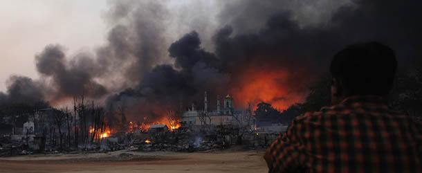 A resident watches as black smoke rises from burning houses in riot-hit Meiktila, central Myanmar on March 21, 2013. At least 10 people have been killed in riots in central Myanmar, an MP said on March 21, prompting international concern at the country's worst communal unrest since a wave of Buddhist-Muslim clashes last year. AFP PHOTO/ Soe Than WIN (Photo credit should read Soe Than WIN/AFP/Getty Images)