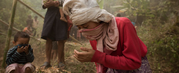 Myanmar refugees cover their mouths as a Thai army helicopter (not pictured) takes off at the Mae Surin camp in Mae Hong Son province on March 24, 2013. Thai rescue workers picked through the ashes of hundreds of shelters for Myanmar refugees, after a ferocious blaze swept through a camp in northern Thailand killing 35 people. AFP PHOTO/ Nicolas ASFOURI (Photo credit should read NICOLAS ASFOURI/AFP/Getty Images)