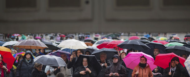 Faithful hold their umbrellas as they follow on a video monitor in St. Peter's Square as cardinals take an oath in the Sistine Chapel at the start the conclave to elect a new pope at the Vatican, Tuesday, March 12, 2013. Cardinals enter the Sistine Chapel on Tuesday to elect the next pope amid more upheaval and uncertainty than the Catholic Church has seen in decades: There's no front-runner, no indication how long voting will last and no sense that a single man has what it takes to fix the many problems. (AP Photo/Emilio Morenatti)