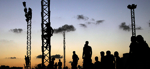 FILE - In this Friday, Sept. 21, 2012 file photo, Libyans climb up electricity towers to watch the march against Ansar al-Shariah Brigades and other Islamic militias, in Benghazi, Libya. More than 18 months since the end of Libya's civil war, the most attractive job for many of the young is still to join a militia. In fact, just under a tenth of Libya's labor force may be working as gunmen. State coffers are full of cash from rapidly reviving oil production, but rather than funding reconstruction, much of the money goes to buying off a restive population with state salaries, including to militias, effectively feeding a cycle of lawlessness. (AP Photo/Mohammad Hannon, File)