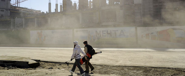 Skiers walk past of the ongoing construction work in Krasnaya Polyana outside the Russian Black Sea resort of Sochi on March 8, 2013. With a year to go until the Sochi 2014 Winter Games, construction work continues as tests events are underway. AFP PHOTO / MIKHAIL MORDASOV (Photo credit should read MIKHAIL MORDASOV/AFP/Getty Images)