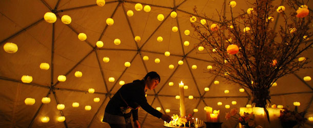 A woman lights candles to pay tribute to the victims of the March 11 earthquake and tsunami at a make-shift alter in a park in Tokyo Sunday, March 10, 2013. Japan observes two years from the earthquake, tsunami and nuclear disaster on March 11. (AP Photo/Junji Kurokawa)