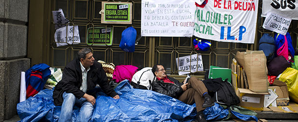 MADRID, SPAIN - OCTOBER 26: Mortgage Victims Platform (PAH) members Domingo Elar Rocha (L), a 55 years old unemployed from Bolivia who has received an eviction notice from his home for the 5th of December, and Angel Rodrigo (R), a 54 years old unemployed from Equador who has not paid his mortgage since June, camp outside an office of Caja Madrid, a major mortgage lender now part of the nationalized Bankia group, during a protest against evictions from their homes on October 26, 2012 in Madrid, Spain. Under Spanish law, banks may claim the full value of a loan on a property whose price has fallen even after evicting the holder of the mortgage. Members of the Mortgage Victims Platform (PAH) are demanding to be cleared from debt when the bank repossesses their property and to stay on as tenants. The nationalized Bankia group, that pushed Spain toward a European bank bailout, announced a 7.05 billion-euro ($9.1 billion) nine-month loss today. (Photo by Jasper Juinen/Getty Images)