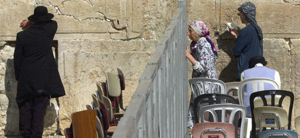 An Ultra Orthodox Jewish woman peeks through a barrier separating prayer sections for men and women at the Western Wall as worshipers pray in Jerusalem's Old City on Sunday, Sept. 23, 2001. (AP Photo/Elizabeth Dalziel)