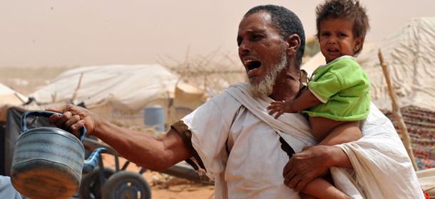 A Malian refugee shouts for water at a distribution point of the Mbere refugee camp on May 3, 2012, near Bassiknou, southern Mauritania, 60 km from the border with Mali. The fighting in Mali has left more than 60,000 people internally displaced, and a similar number have fled to Mauritania and neighboring countries. Camp Mbere, spread out over a surface area of some 570 km2 receives an average of 1,000 refugees per day, some days even more. According to the LWF representative, in mid-April the camp population was over 55,000, of which more than half were children. AFP PHOTO / ABDELHAK SENNA (Photo credit should read ABDELHAK SENNA/AFP/GettyImages)