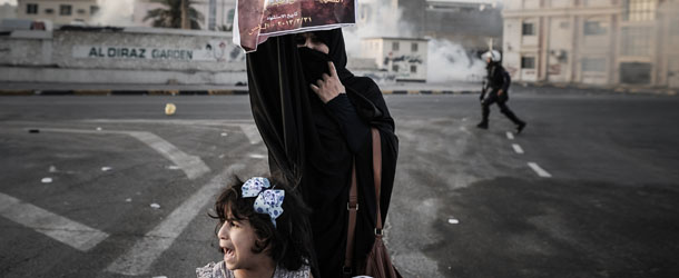 A Bahraini woman, standing with her daughter, holds up a picture of Abd Al-Ghani Al-Rayes during clashes following his funeral procession in the village of Diraz, west of Manama on April 1, 2013. Al-Rayes, who was 66-years old, died in front of a police station following what medics presume was a heart-attack, as he was trying to find out what happened to his arrested son, family said. AFP PHOTO/MOHAMMED AL-SHAIKH (Photo credit should read MOHAMMED AL-SHAIKH/AFP/Getty Images)