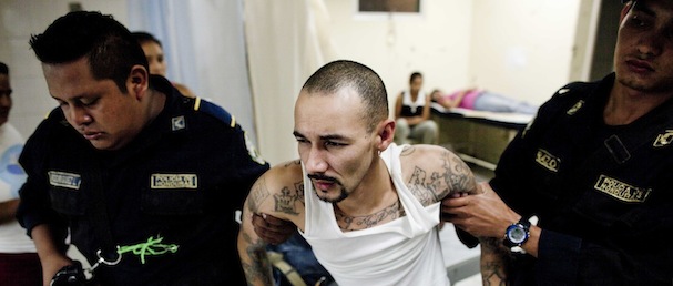 In this March 23, 2013 photo, police officers escort a member of the Mara 18 gang inside the emergency room of the public hospital in San Pedro Sula, Honduras. With 91 murders per 100,000 people, the small Central American nation is often called the most violent in the world. The homicide rate is roughly 20 times that of the U.S. rate, according to a 2011 United Nations report. (AP Photo/Esteban Felix)