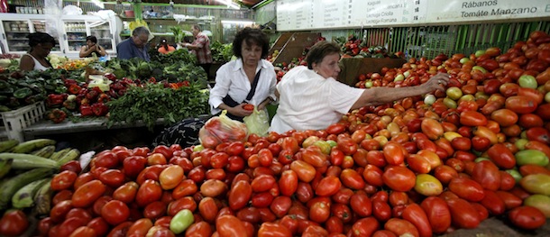 In this April 6, 2013 photo, customers choose tomatoes at a food market in Caracas, Venezuela. Venezuelans complain that what goes into their Sunday dinner plate comes from abroad: Steak, from Brazil; plantains, the Dominican Republic; rice, South Africa; Parmesan cheese, Uruguay; oats, Chile. Even coffee, in a country famed for it, often is Colombian. (AP Photo/Fernando Llano)