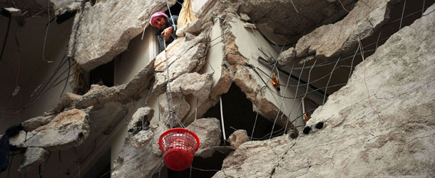A Syrian man lowers a basket filled with some belongings as civilians collect items from their damaged apartments before fleeing the northern Syrian city of Aleppo on April 10, 2013. The United States is mulling ways to step up support for the Syrian opposition, a top US official said, as US Secretary of State John Kerry and G8 ministers were to meet rebel leaders. AFP PHOTO / DIMITAR DILKOFF (Photo credit should read DIMITAR DILKOFF/AFP/Getty Images)