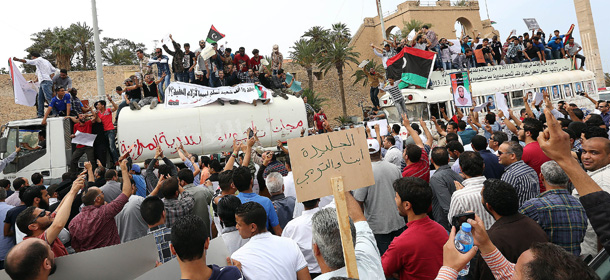 Libyan protesters hold placards and banners during a demonstration in support of the "political isolation law" in Libya's landmark Martyrs Square on May 5, 2013 in Tripoli, Libya. Libya's General National Congress, under pressure from armed militias, voted through a controversial law to exclude former regime officials from government posts. Gunmen who had surrounded the foreign and justice ministries to press for officials from the regime of the late dictator Moamer Kadhafi to be sacked from top government jobs lifted the sieges when state television broke the news. AFP PHOTO/MAHMUD TURKIA (Photo credit should read MAHMUD TURKIA/AFP/Getty Images)