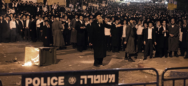 A religious leader (C) tries to calm the crowd as thousands Ultra Orthodox Jews clash with Israeli police forces in Jerusalem on May 16, 2013 during a protest in front of the main army recruitment office to demonstrate against any plans to make them undergo military service, a police spokesman said. Protesters also prayed and chanted "the Torah above everything!" referring to Jewish religious law, and "the army will not take yeshiva (religious seminary) pupils." AFP PHOTO / MARCO LONGARI (Photo credit should read MARCO LONGARI/AFP/Getty Images)