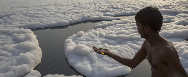 NEW DELHI, INDIA - MAY 24: An Indian man makes an offering on the banks of an industrial waste-foam polluted section of the Yamuna River, on the outskirts of New Delhi on May 24, 2013 in New Delhi, India. The Yamuna river, holy to Hindus, traverses various urban centers like Delhi, Mathura, and Agra. These large urban centers draw fresh river water for various activities. In return, almost the entire waste water generated by these centers is disposed off into the river. This is the prime reason for deterioration of Yamuna River water quality, according to the Central Pollution Control Board of India. (Photo by Daniel Berehulak/Getty Images)