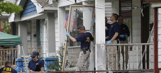 Members of the FBI evidence response team carry out the front screen door from a house Tuesday, May 7, 2013, where three women were held, in Cleveland. Three women who disappeared a decade ago were found safe Monday, and police arrested three brothers accused of holding the victims against their will. (AP Photo/Tony Dejak)
