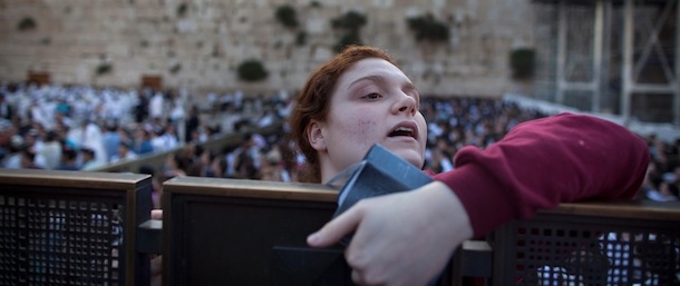 JERUSALEM, ISRAEL - MAY 10: An Ultra Orthodox Jewish girl looks at members of the religious group 'Women Of The Wall' hold a prayer service to mark the first day of the Jewish month of Sivan at the Western Wall on May 10, 2013 in Jerusalem, Israel. Thousands of ultra-Orthodox protestors clashed with Israeli police during the first monthly prayer service to be held by Women Of The Wall following the recent landmark ruling by Jerusalem District Court allowing women to wear prayer shawls at the Western Wall. (Photo by Uriel Sinai/Getty Images)