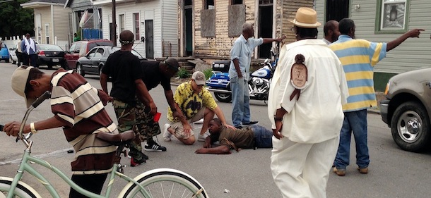 Bystanders comfort a shooting victim while awaiting EMS at the intersection of Frenchmen and N. Villere Streets after authorities say gunfire injured at least a dozen people, including a child, at a Mother's Day second-line parade in New Orleans on Sunday, May 12, 2013. No deaths were reported. (AP Photo/The Times-Picayune, Lauren McGaughy)