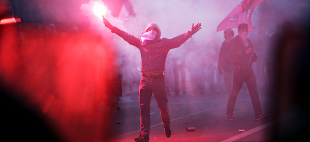 An anti-gay marriage demonstrator lifts a flair as he faces riot police (not seen) while teargas canisters smoke during clashes in Paris, France, Sunday May 26, 2013. Tens of thousands of people protested against France's new gay marriage law in central Paris on Sunday. The law came into force over a week ago, but organizers decided to go ahead with the long-planned demonstration to show their continued opposition as well as their frustration with President Francois Hollande, who had made legalizing gay marriage one of his keynote campaign pledges in last year's election.(AP Photo/Thibault Camus)