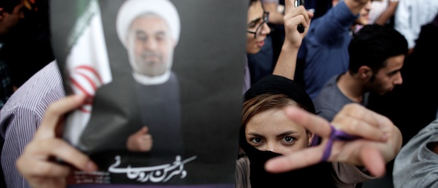 An Iranian woman flashes the sign for victory as she holds a portrait of moderate presidential candidate Hassan Rowhani during celebrations for his victory in the Islamic Republic's presidential elections in downtown Tehran on June 15, 2013. Iranian Interior Minister Mohammad Mostafa Najjar said Rowhani won outright with 18.6 million votes, or 50.68 percent. AFP PHOTO/BEHROUZ MEHRI (Photo credit should read BEHROUZ MEHRI/AFP/Getty Images)
