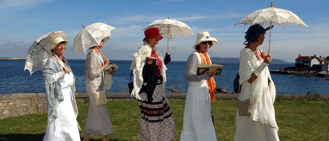 Five unidentifed women, one of whom reads from "Ulysses," walk along Sandycove in period dress in Dublin, Ireland, Wednesday June 16, 2004, during "Bloomsday," the 100th anniversary commemoration of the day on which James Joyce set the fictional journey of his character Leopold Bloom 100 years ago. (AP Photo/John Cogill)