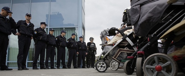 Bosnian women and their babies protest in front of the Bosnian parliament building as police officers stand guard in Sarajevo, Thursday, June 6, 2013. Nearly 3,000 people formed a chain around Bosnia's parliament Thursday, saying they won't let politicians go home until they start doing their jobs instead of keeping the country paralyzed with ethnic bickering. What started as a small protest over a new law on personal identification numbers the day before has grown into a blockade of the building, with more people joining the protest every hour. (AP Photo/Amel Emric)