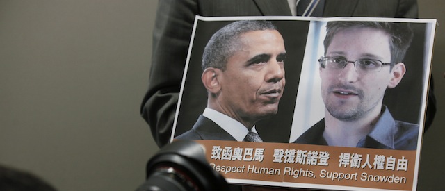 A photographer takes picture of U.S president Obama and Edward Snowden hold by pro-democractic legislator Gary Fan Kwok-wai during a news conference in Hong Kong Friday, June 14, 2013. Mo concerned about the implications for freedom everywhere of the information disclosed by Edward Snowden and urge Obama to listen to democrats in a Hong Kong which finds itself Snowden's temporary refuge. (AP Photo/Kin Cheung)