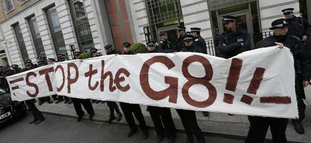 Demonstrators hold up a banner against the G8 outside the headquarters of British based oil multinational BP during a protest in London, Tuesday, June 11, 2013 .The protestors were demonstrating against the upcoming G8 summit in Northern Ireland on June 17 and 18.(AP Photo/Alastair Grant)