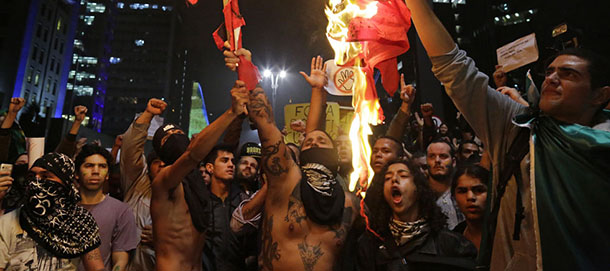 Demonstrators burn flags of the Workers' Party on Paulista Avenue where crowds gathered to celebrate the reversal of a fare hike on public transportation, in Sao Paulo, Brazil, Thursday, June 20, 2013. After a week of mass protests, Brazilians won the world's attention and a pull-back on the subway and bus fare hikes that had first ignited their rage. Protesters gathered for a new wave of massive demonstrations in Brazil on Thursday evening, extending the protests that have sent hundreds of thousands of people into the streets since last week to denounce poor public services and government corruption. (AP Photo/Nelson Antoine)