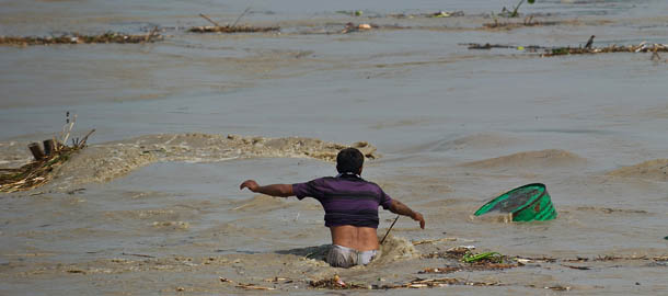 An Indian man tries to catch an oil container being carried away in the rising waters of the Yamuna river in New Delhi on June 19, 2013. The monsoon, which India's farming sector depends on, covers the subcontinent from June to September, usually bringing some flooding. But the heavy rains arrived early this year, catching many by surprise and exposing the country's lack of preparedness. Military helicopters dropped emergency supplies to thousands of tourists and pilgrims stranded by flash floods that tore through towns and temples in northern India, killing at least 120 people, officials said. AFP PHOTO/ Prakash SINGH (Photo credit should read PRAKASH SINGH/AFP/Getty Images)