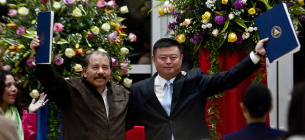 Nicaragua's President Daniel Ortega, left, and Chinese businessman Wang Jing hold up a concession agreement for the construction of a multibillion-dollar canal at the Casa de los Pueblos in Managua, Nicaragua, Friday, June 14, 2013. In a matter of weeks, Wang Jing has hired some of the world's top experts in mammoth infrastructure projects and pushed through Nicaragua's congress a bill granting him the exclusive right to develop a multibillion-dollar rival to the Panama Canal. (AP Photo/Esteban Felix)