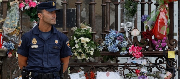 SANTIAGO DE COMPOSTELA, SPAIN - JULY 29: A police officer stands in front of an improved memorial altar as he guards Obradoiro gate of Santiago de Compostela Cathedral, prior to start the memorial Mass for the vitims of the Spanish train crash on July 29, 2013 in Santiago de Compostela, Spain. The high speed train crashed after it derailed on a bend as it approached the north-western Spanish city of Santiago de Compostela at 8:40pm on July 24th, the eve of the Santiago de Compostela Festivities. At least 79 people have died and a further 130 are reported injured. The train driver, Garzon Amo, has been formally accused of reckless homicide and has been released with charges after attending court. (Photo by Gonzalo Arroyo Moreno/Getty Images)