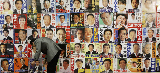 TOKYO, JAPAN - SEPTEMBER 11: A hotel employee cleans the floor in front of Democratic Party of Japan campaign posters at a Tokyo hotel uses to hear election results September 11, 2005 in Tokyo, Japan. The election was to determine who would win the 480 seats in the lower house. (Photo by Junko Kimura/Getty Images)