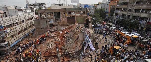 Indians watch as Indian Fire officials and rescue workers look for survivors at the site of collapsed building, in Hyderabad, India, Monday, July 8, 2013. An official says at least ten people have been killed and 12 others injured after a two-story hotel collapsed in southern India (AP Photo/Mahesh Kumar A.)