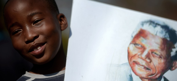 A child smiles while holding a portrait of Nelson Mandela outside the Mediclinic Heart Hospital in Pretoria where the ailing former South Africa's president is hospitalised on June 29, 2013. Mandela, who turns 95 next month, was rushed to hospital three weeks ago with a recurrent lung disease. AFP PHOTO / FILIPPO MONTEFORTE (Photo credit should read FILIPPO MONTEFORTE/AFP/Getty Images)