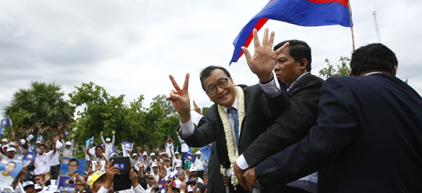 Cambodian opposition leader Sam Rainsy gestures as he greets supporters of his Cambodia National Rescue Party upon arrival at Phnom Penh International Airport in Phnom Penh, Cambodia, Friday, July 19, 2013. Thousands of cheering supporters greeted Sam Rainsy as he returned from self-imposed exile Friday to spearhead his party's election campaign against well-entrenched Prime Minister Hun Sen. (AP Photo/Heng Sinith)