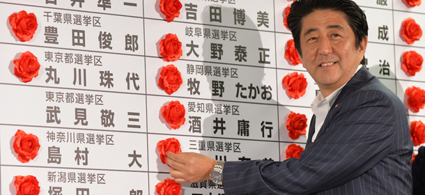 Japanese Prime Minister and President of the Liberal Democratic Party (LDP), Shinzo Abe places a red paper rose on a LDP candidate's name to indicate an election victory at the party's headquarters in Tokyo on July 21, 2013. Voters gave Prime Minister Shinzo Abe a resounding victory in upper house elections July 21, exit polls showed, likely ushering in a new period of stability for politically volatile Japan. AFP PHOTO / KAZUHIRO NOGI (Photo credit should read KAZUHIRO NOGI/AFP/Getty Images)