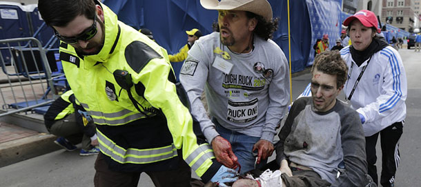 AP10ThingsToSee - An emergency responder and volunteers, including Carlos Arredondo in the cowboy hat, push Jeff Bauman in a wheel chair after he was injured in an explosion near the finish line of the Boston Marathon Monday, April 15, 2013 in Boston. At least three people were killed, including an 8-year-old boy, and more than 170 were wounded when two bombs blew up seconds apart. (AP Photo/Charles Krupa, File)