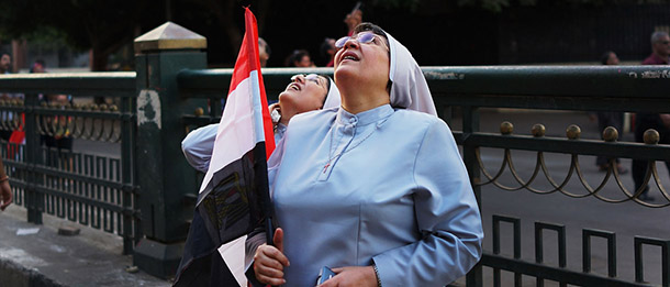 CAIRO, EGYPT - JULY 04: Two nuns look up at Egyptian military aircraft as they fly over Tahrir Square, the day after former Egyptian President Mohammed Morsi, the country's first democratically elected president, was ousted from power on July 4, 2013 in Cairo, Egypt. Adly Mansour, chief justice of the Supreme Constitutional Court, was sworn in as the interim head of state in ceremony in Cairo in the morning of July 4, the day after Morsi was placed under house arrest by the Egyptian military and the Constitution was suspended. (Photo by Spencer Platt/Getty Images)