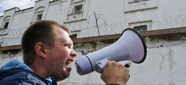 A Russian opposition leader Alexei Navalny supporter uses a loudspeaker outside a temporary detention center, where Russian opposition leader Alexei Navalny is reportedly kept, in Kirov, Russia Thursday, July 18, 2013. Alexei Navalny, one of the Russian opposition's leading figures, was convicted of embezzlement Thursday and sentenced to five years in prison. (AP Photo/Evgeny Feldman)