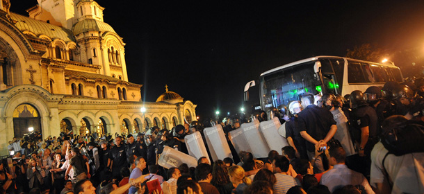 Bulgarian riot policemen push protestors back to make way for the bus with lawmakers and parliament staff during an anti-government protest in Sofia on July 23, 2013. Bulgarian protesters clashed with police on the 40th evening of massive anti-government rallies in the EU's poorest country Tuesday after blockading ministers, lawmakers and journalists inside parliament for over five hours. AFP PHOTO / DIMITAR DILKOFF (Photo credit should read DIMITAR DILKOFF/AFP/Getty Images)
