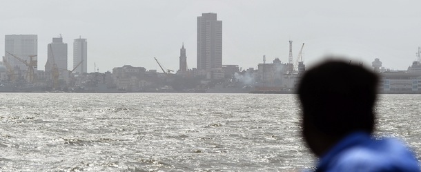 A tourist looks on from a boat as exhaust smoke rises from an Indian Navy vessel at the Naval Dockyard, the site where an Indian submarine exploded and sank, in Mumbai on August 14, 2013. India's navy said all 18 sailors on board a submarine which exploded and sank on August 14 are feared dead, and admitted the incident had left a "dent" in the country's defences. AFP PHOTO/ INDRANIL MUKHERJEE (Photo credit should read INDRANIL MUKHERJEE/AFP/Getty Images)