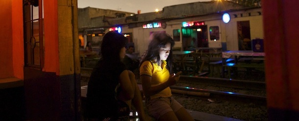 JAKARTA, INDONESIA - AUGUST 27: A woman checks her phone in front of a small bar just meters from a busy railway track in a brothel area on August 27, 2013 in Jakarta, Indonesia. Brothel areas are one of the main battlegrounds for HIV prevention, and outreach workers are trying to stem the growth of the disease, which over the past decade has risen by 25 percent. Indonesia is one of relatively few countries where infection has rapidly increased. (Photo by Ed Wray/Getty Images)
