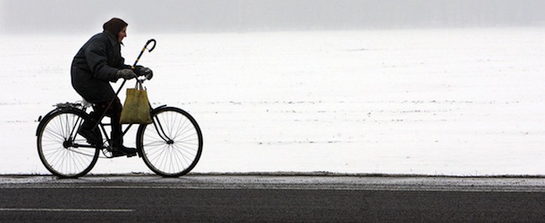KOBRIN, BELARUS: Picture taken 15 February 2007 shows an elderly woman riding her bicycle along a road near the Belarus's town of Kobrin, some 280 km southwest of Minsk. AFP PHOTO / VIKTOR DRACHEV (Photo credit should read VIKTOR DRACHEV/AFP/Getty Images)