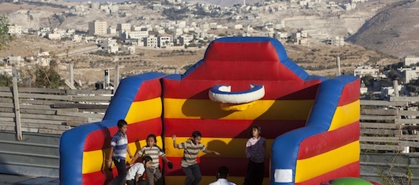 Israeli children play near a construction site during a ceremony to mark the resumption of the construction of housing units in an east Jerusalem neighborhood, Sunday, Aug. 11, 2013. Israel's housing minister on Sunday gave final approval to build nearly 1,200 apartments in Jewish settlements, just three days before Israeli-Palestinian peace talks are to resume in Jerusalem. (AP Photo/Sebastian Scheiner)