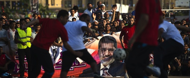 Members of the Muslim Brotherhood and supporters of deposed Egyptian president Mohamed Morsi from two main Cairo protest camps set up at the Nahda and Rabaa al-Adawiya squares play football as backers of the ousted Islamist leader cheer them on and hold a huge poster of Morsi on August 11, 2013 in Cairo's al-Nahda square. The tent camps in Rabaa al-Adawiya and Al-Nahda squares were set up after the Egyptian army deposed president Mohamed Morsi on July 3, and the protesters have sworn to stay put until their man is back in power. AFP PHOTO/ KHALED DESOUKI (Photo credit should read KHALED DESOUKI/AFP/Getty Images)