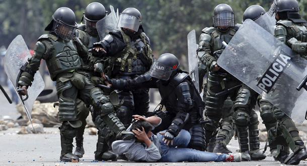 A riot police officer, left, kicks a protesters as another, center, tries to protect him during protests in Ubate, north of Bogota, Colombia, Monday, Aug. 26, 2013. Hundred of protesters clashed with police in support of farmers who have being blockading Colombian highways for a week for an assortment of demands that include reduced gasoline prices, increased subsidies and the cancellation of free trade agreements. (AP Photo/Fernando Vergara)