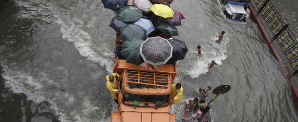 A truckload of stranded commuters cross a flooded street in Manila, Philippines Monday, Aug. 19, 2013. Torrential rains brought the Philippine capital to a standstill Monday, submerging some areas in waist-deep floodwaters and making streets impassable to vehicles while thousands of people across coastal and mountainous northern regions fled to emergency shelters. (AP Photo/Aaron Favila)