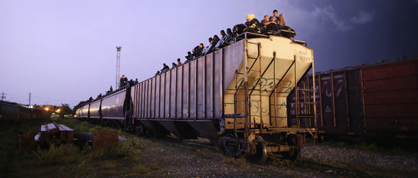 ARRIAGA, MEXICO - AUGUST 04: Central American migrants sit atop a freight train as lightning flashes early on August 4, 2013 in Arriaga, Mexico. Thousands of immigrants ride atop the trains, known as "la bestia," or the beast, during their long and perilous journey through Mexico to the U.S. border. Many of the immigrants are robbed or assaulted by gangs who control the train tops, while others fall asleep and tumble down, losing limbs or perishing under the wheels of the trains. Only a fraction of the immigrants who start the journey will arrive safely on their first attempt to illegally enter the United States. (Photo by John Moore/Getty Images)